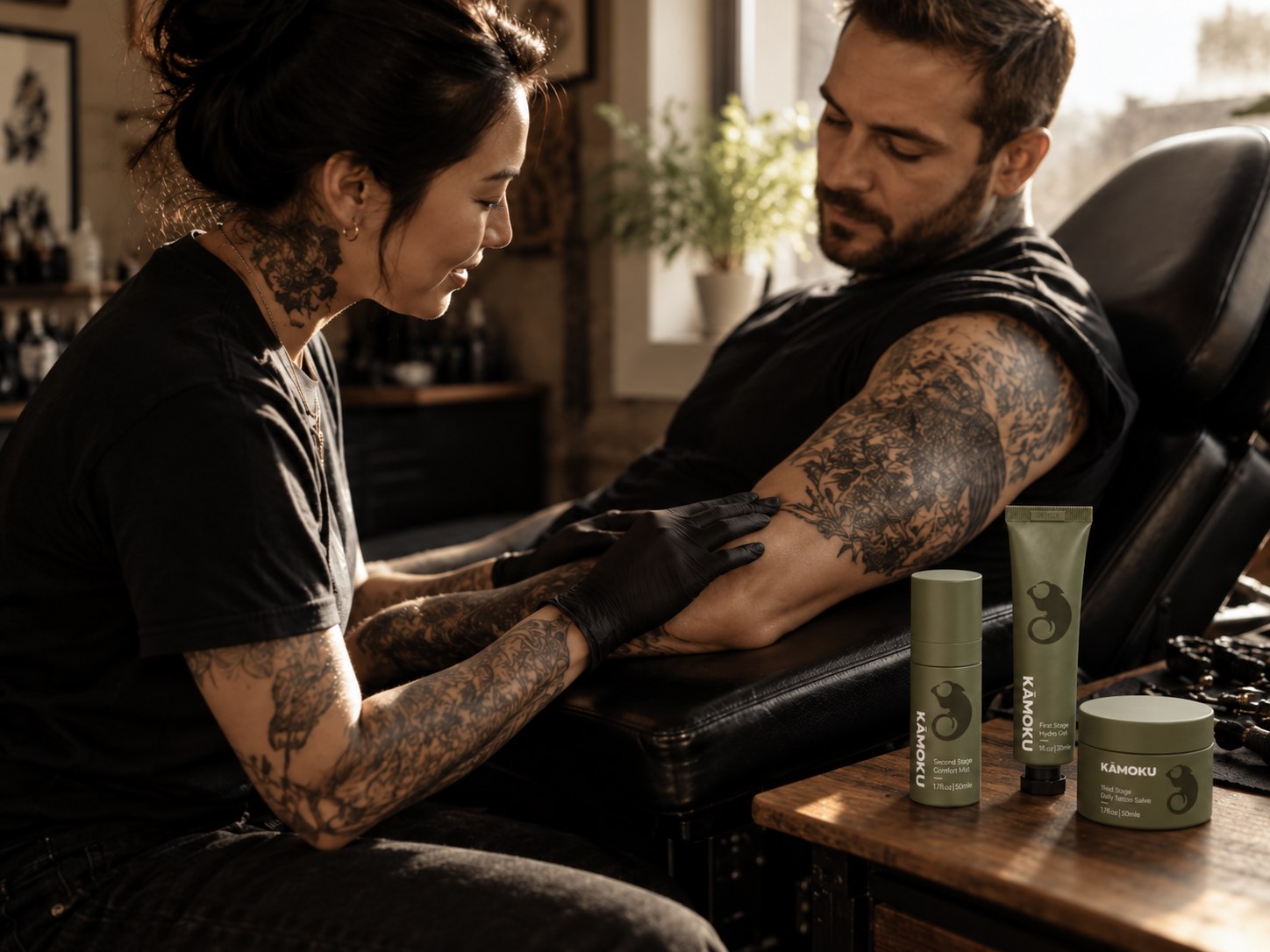 A tattoo artist caring for a client’s arm beside the KĀMOKU three-product set