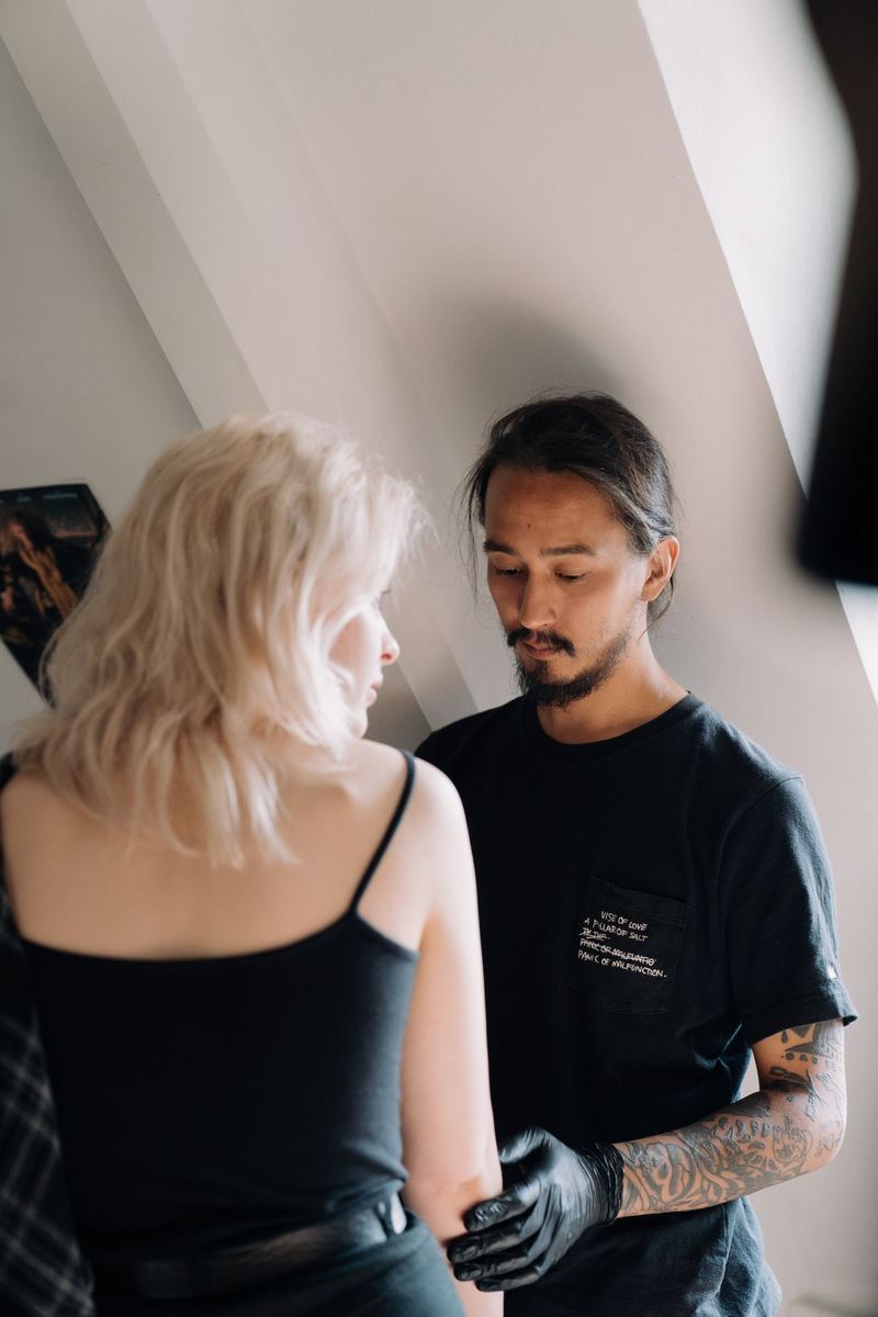 A tattoo artist and a client preparing for an appointment in a sunlit studio