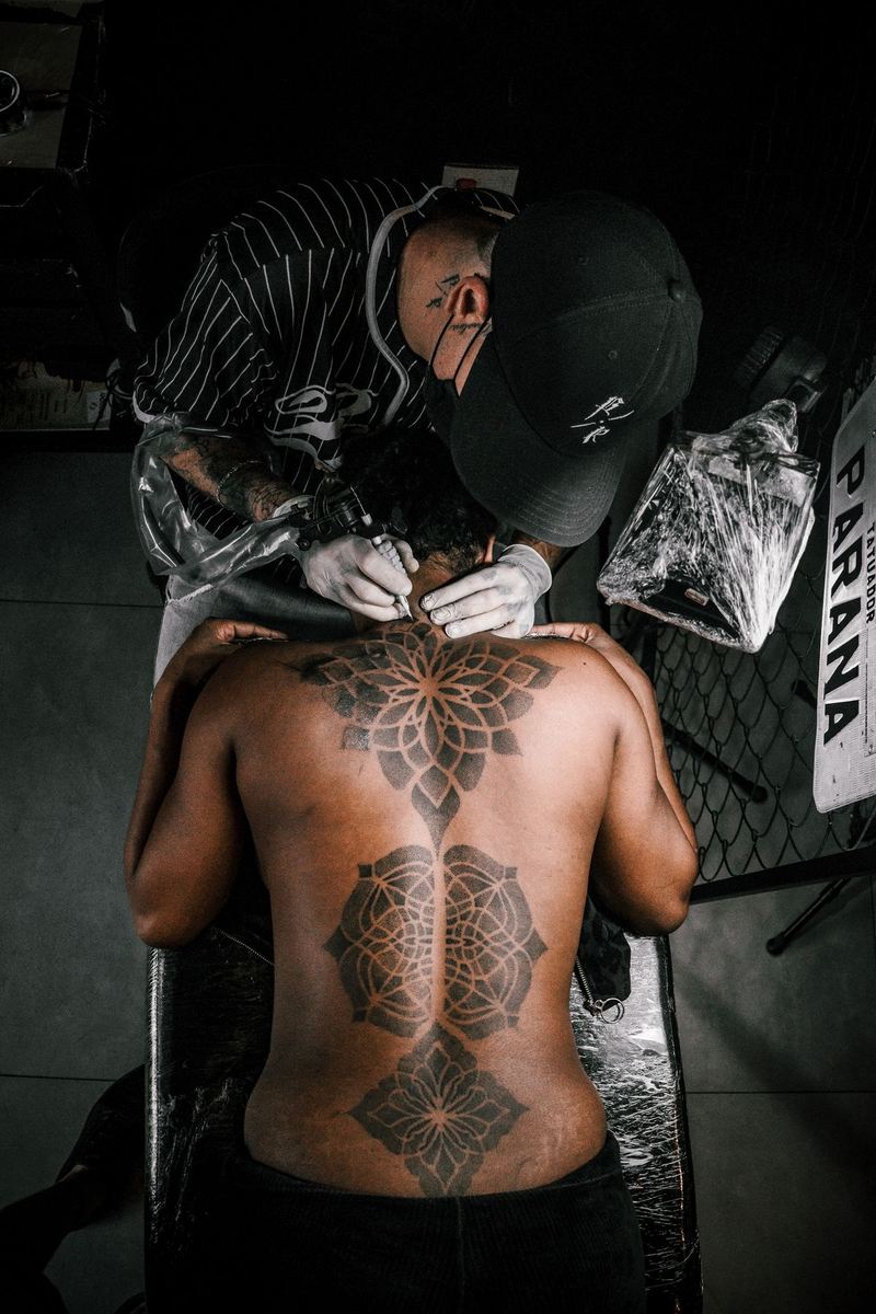 A tattoo artist working on an intricate geometric back tattoo